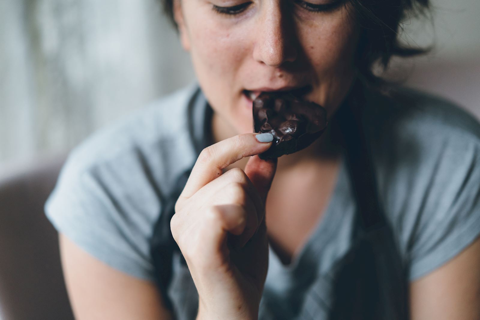 woman eating piece of dark chocolate