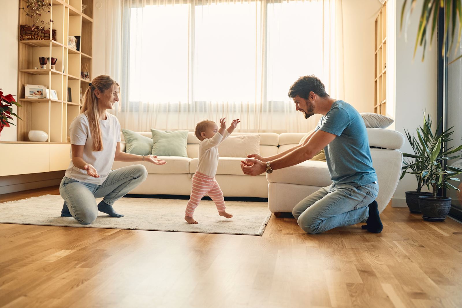 child taking their first steps with their parents