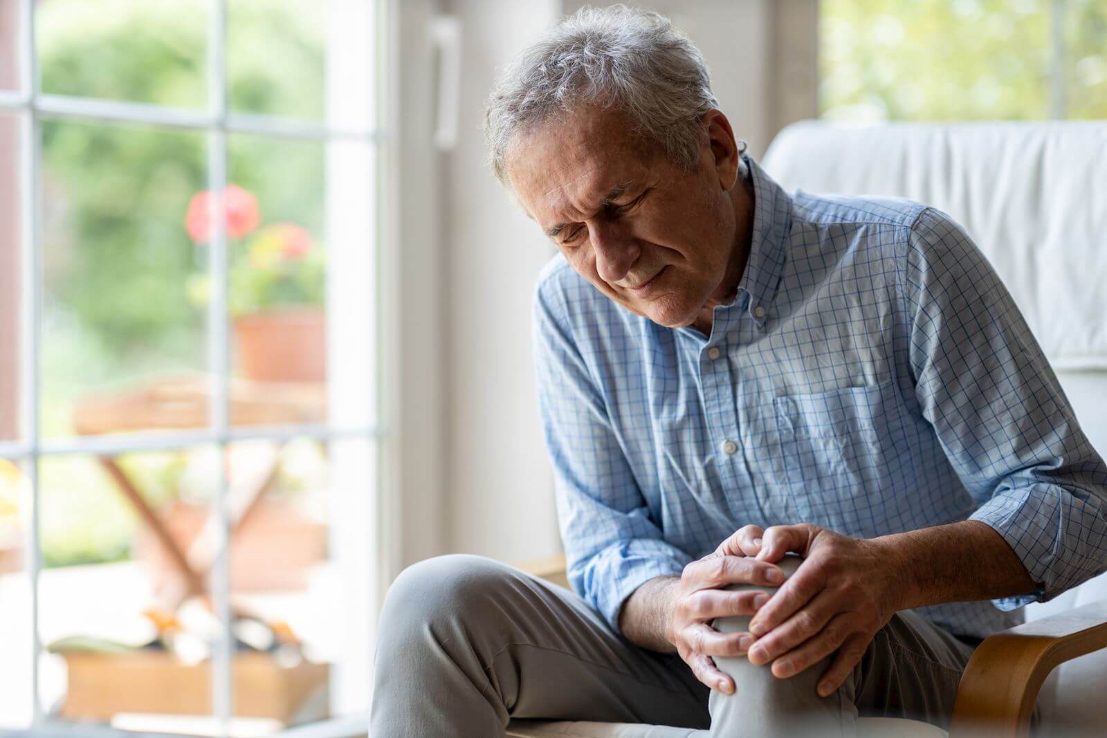 older man holding knee in pain