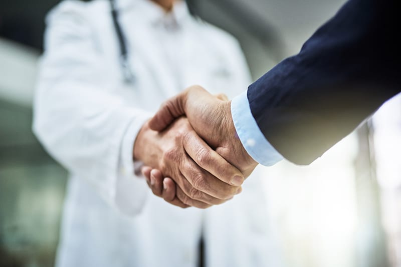 businessperson shaking hands with a doctor
