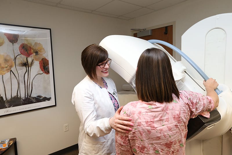 doctor helps woman near mammogram machine