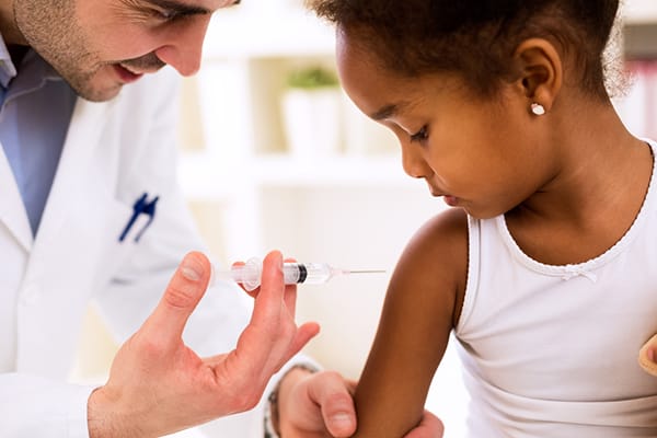 doctor prepares to vaccinate a little girl