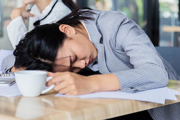 woman with coffee mug asleep on desk