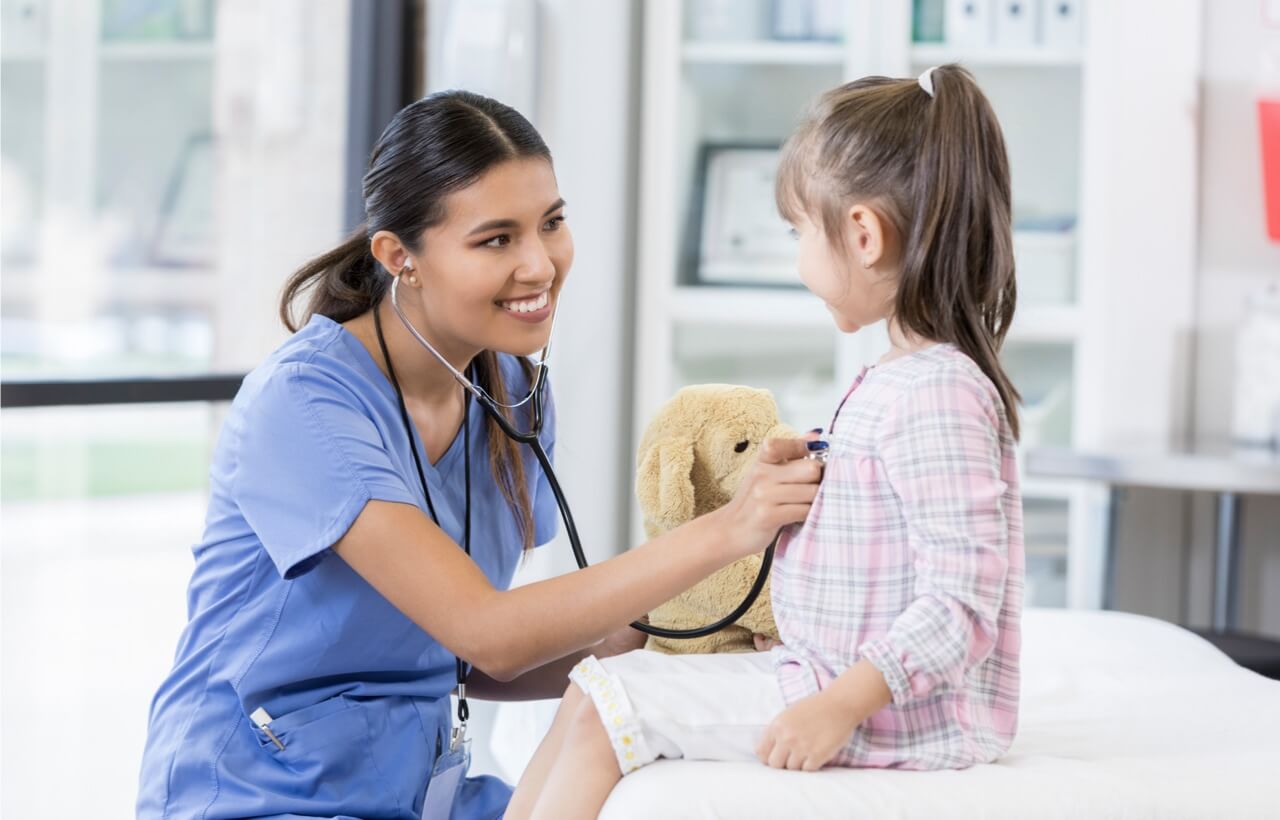 Doctor checking little girl's heart
